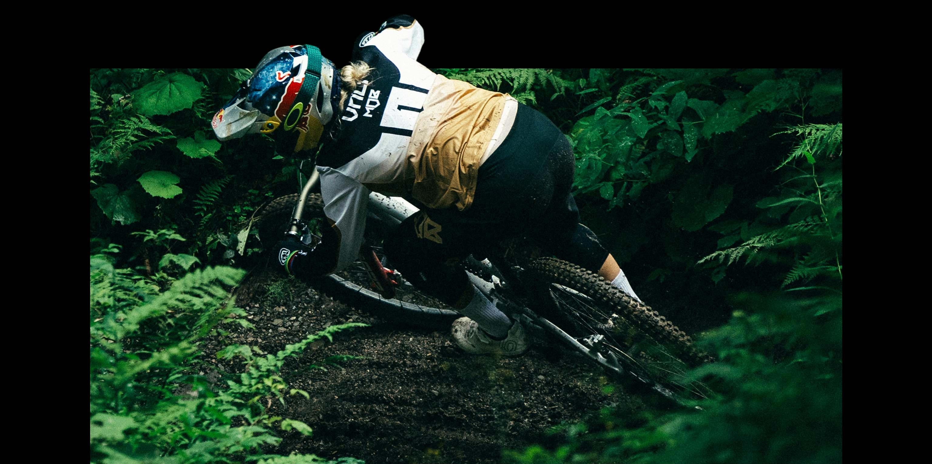 Overhead shot of Vali riding her bike through the dark green of the forest.